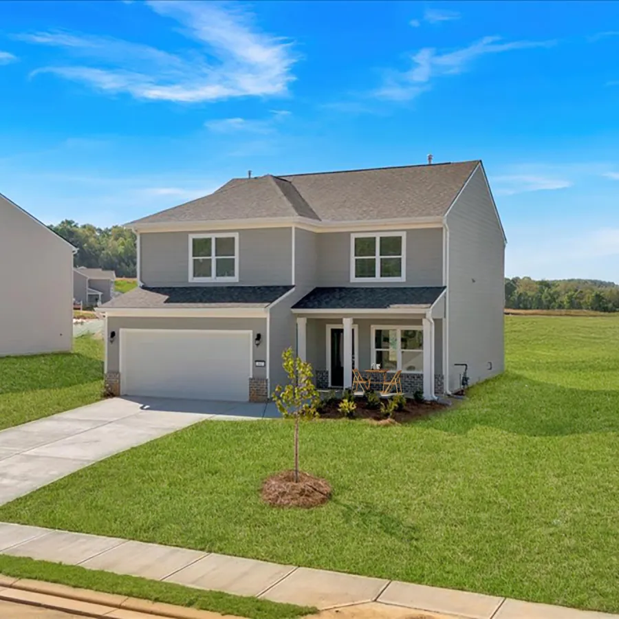 Modern suburban home with driveway and well-kept lawn under a bright blue sky.