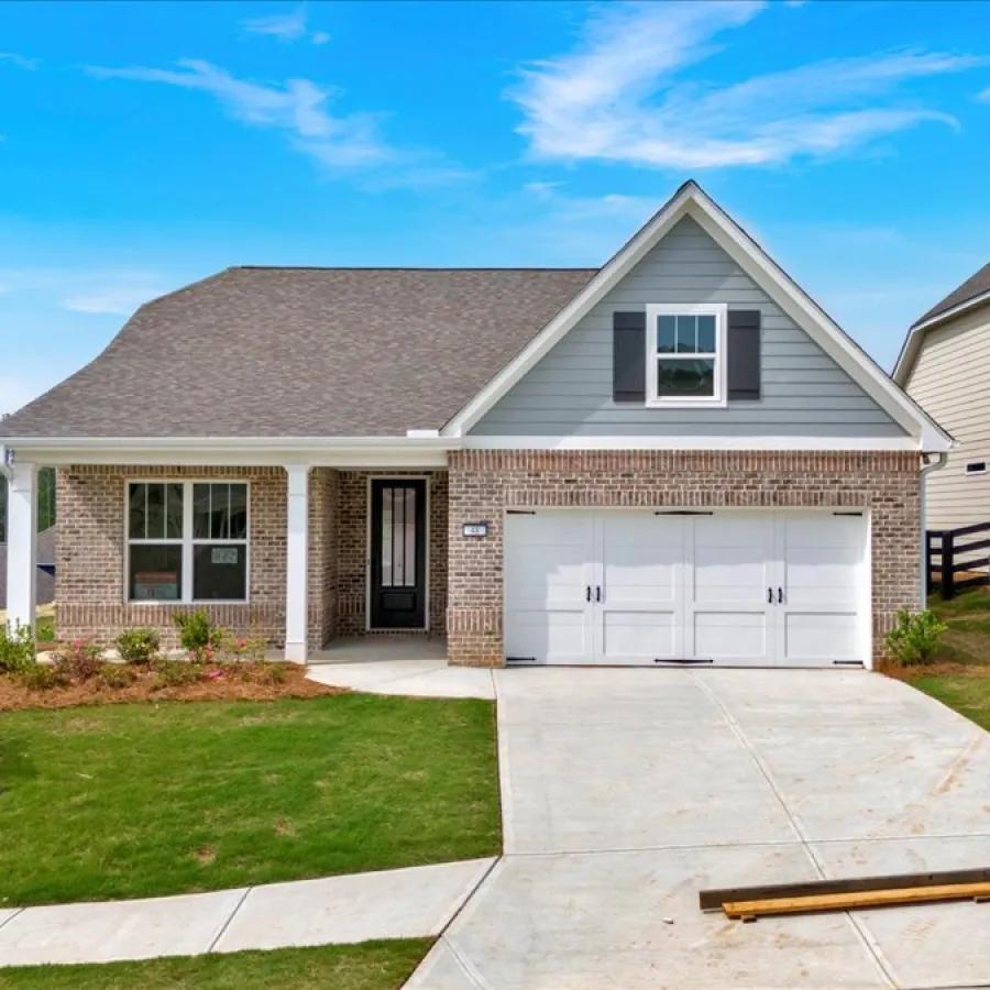 Modern single-story brick house with a two-car garage and a green lawn under a bright blue sky