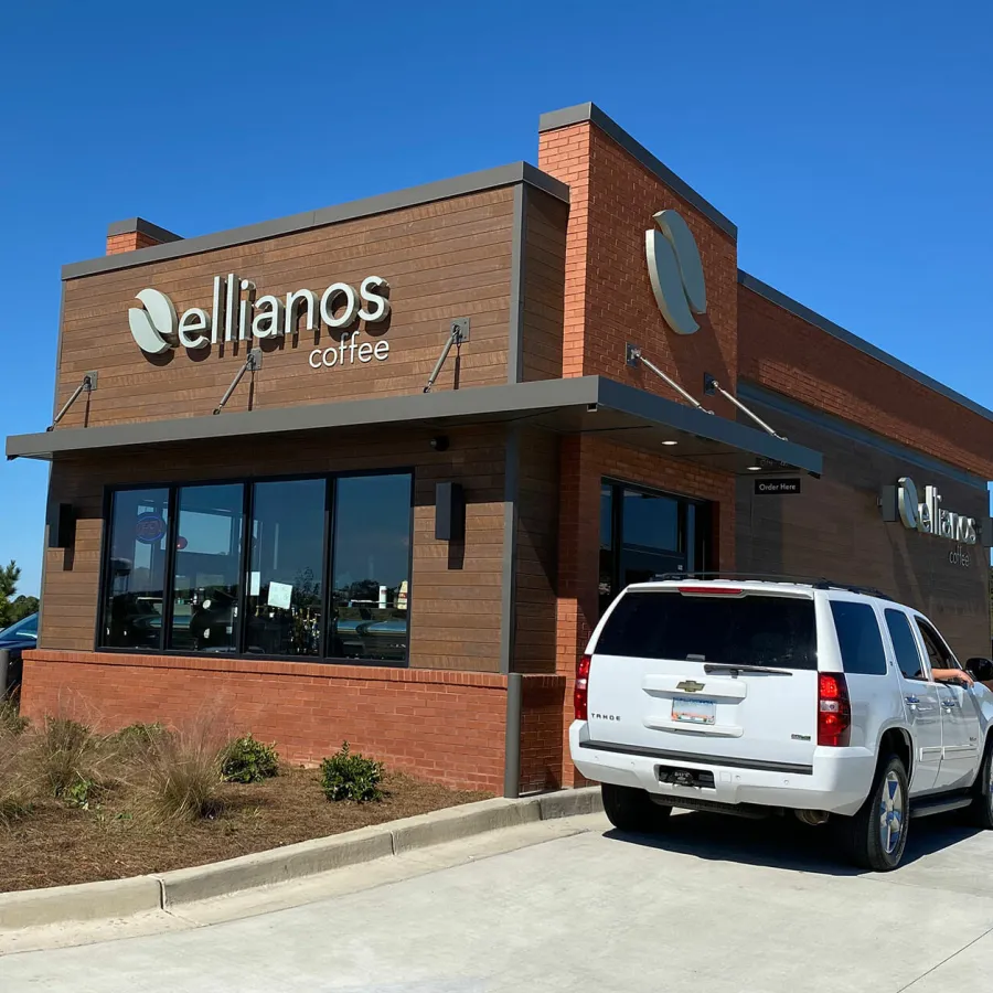 Ellianos Coffee drive-thru shop with a white SUV in the ordering lane on a sunny day.
