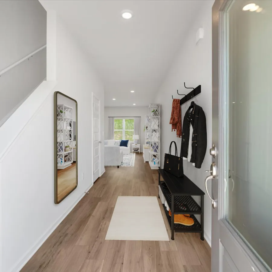 Bright entryway with wood flooring, staircase, mirror, coat rack, bench, and view into living room with large window.
