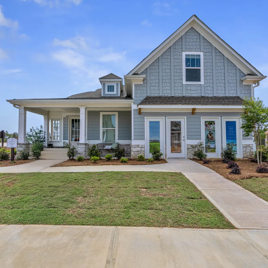 Beautiful modern house with light blue siding, manicured lawn, and clear blue sky in the background.
