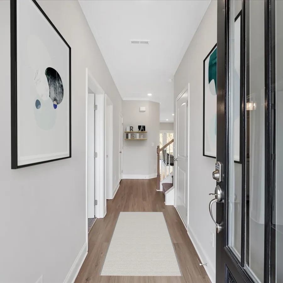 Modern home entryway with wooden floor, white walls, abstract wall art, and a black front door.