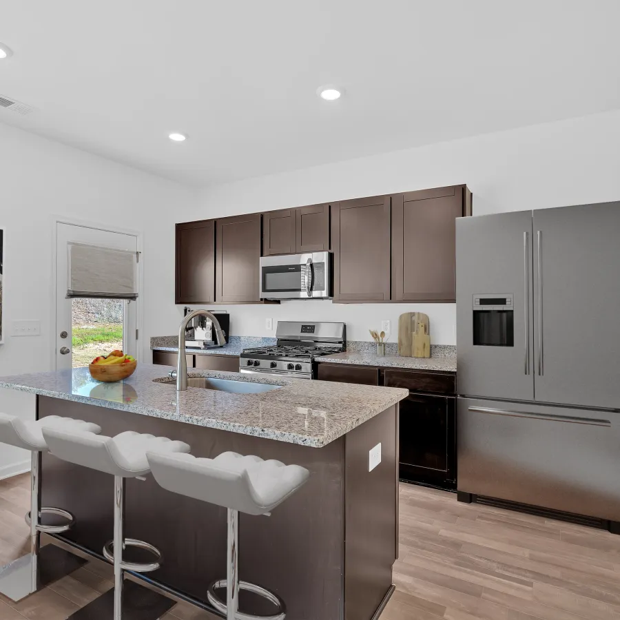 Modern kitchen with dark cabinets, granite countertop, stainless steel appliances, and spacious island seating.