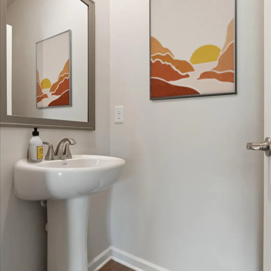 Modern white bathroom sink with silver faucet, decorative landscape art, and wooden floor in neutral walls.