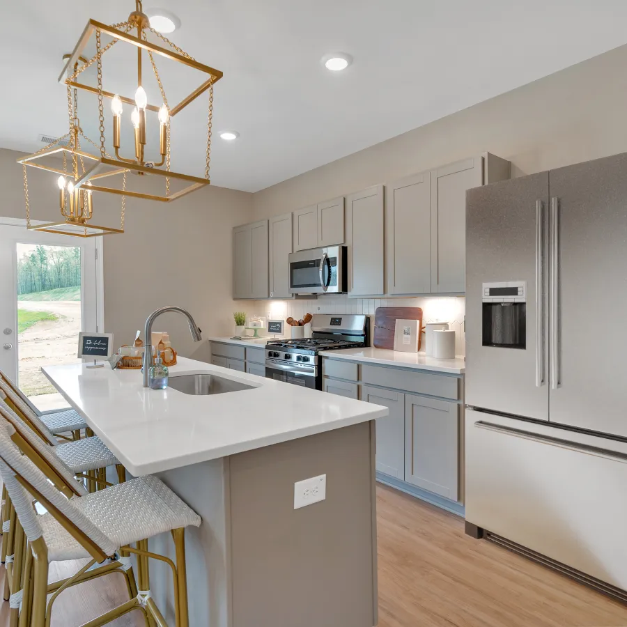 Modern kitchen featuring stainless steel appliances, white countertops, and stylish light fixtures.