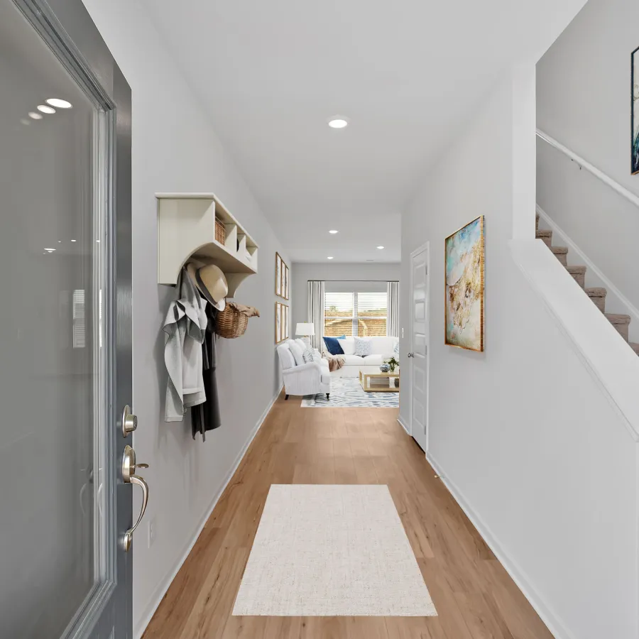 Modern entryway with light walls, wood flooring, and staircase leading to cozy living space.
