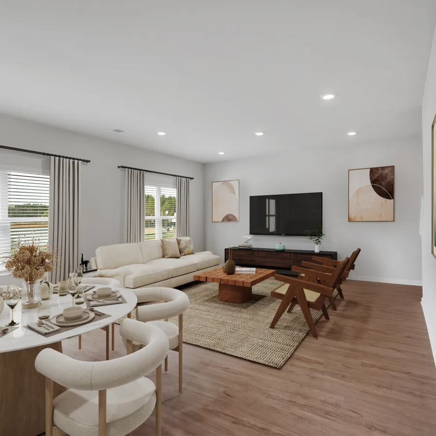 Modern living room with white sofa, wooden chairs, round dining table set, neutral decor, and large windows with curtains