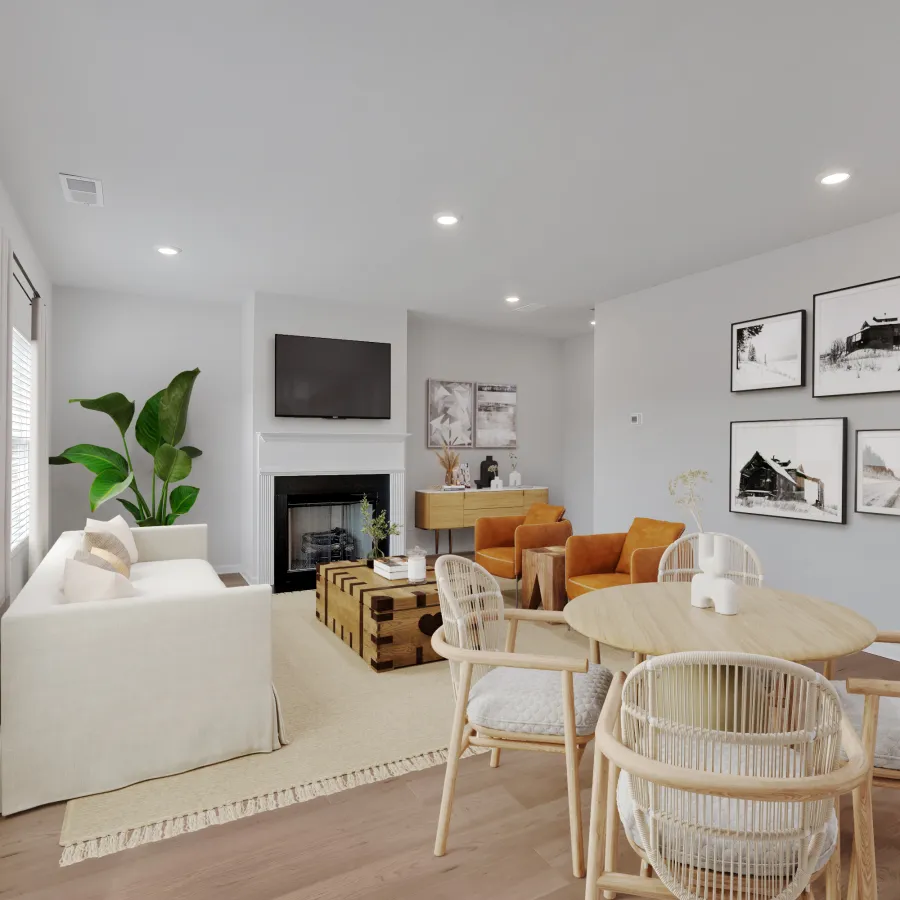 Bright modern living room with white sofa, wooden dining table, orange chairs, and fireplace under TV.
