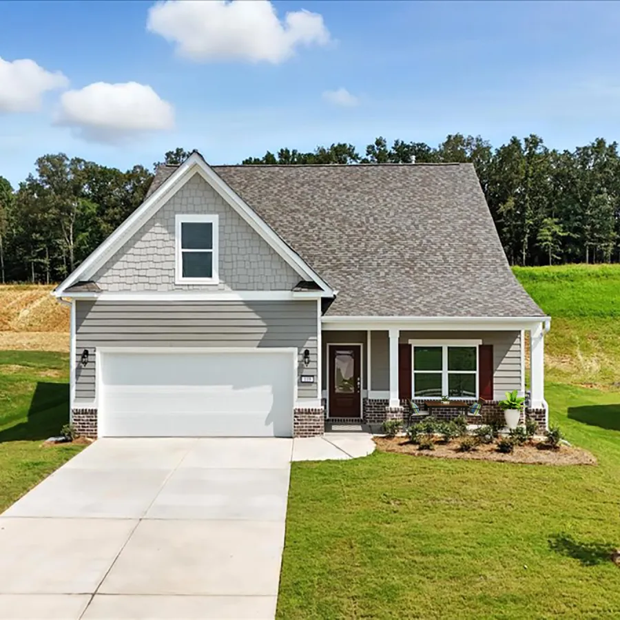 Modern single-family house with gray siding, front porch, two-car garage, and green lawn under a blue sky