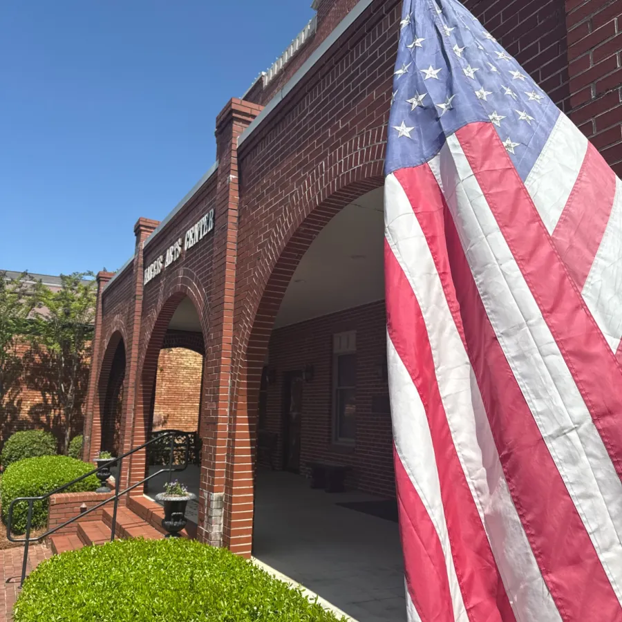 American flag waving in front of a red brick building on a sunny day.