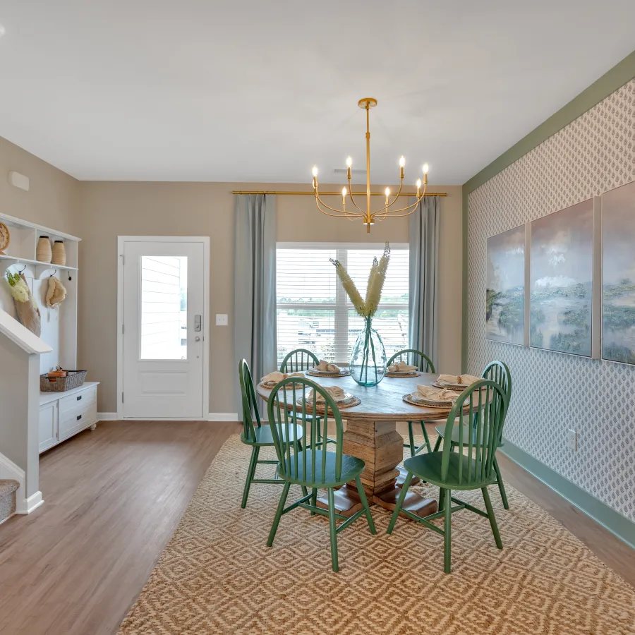 Bright dining area with green chairs, round table, and elegant decor in modern home setting.