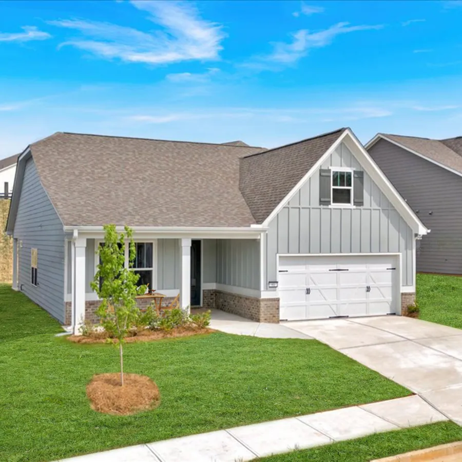 Modern single-story gray house with white garage door and green lawn under a blue sky
