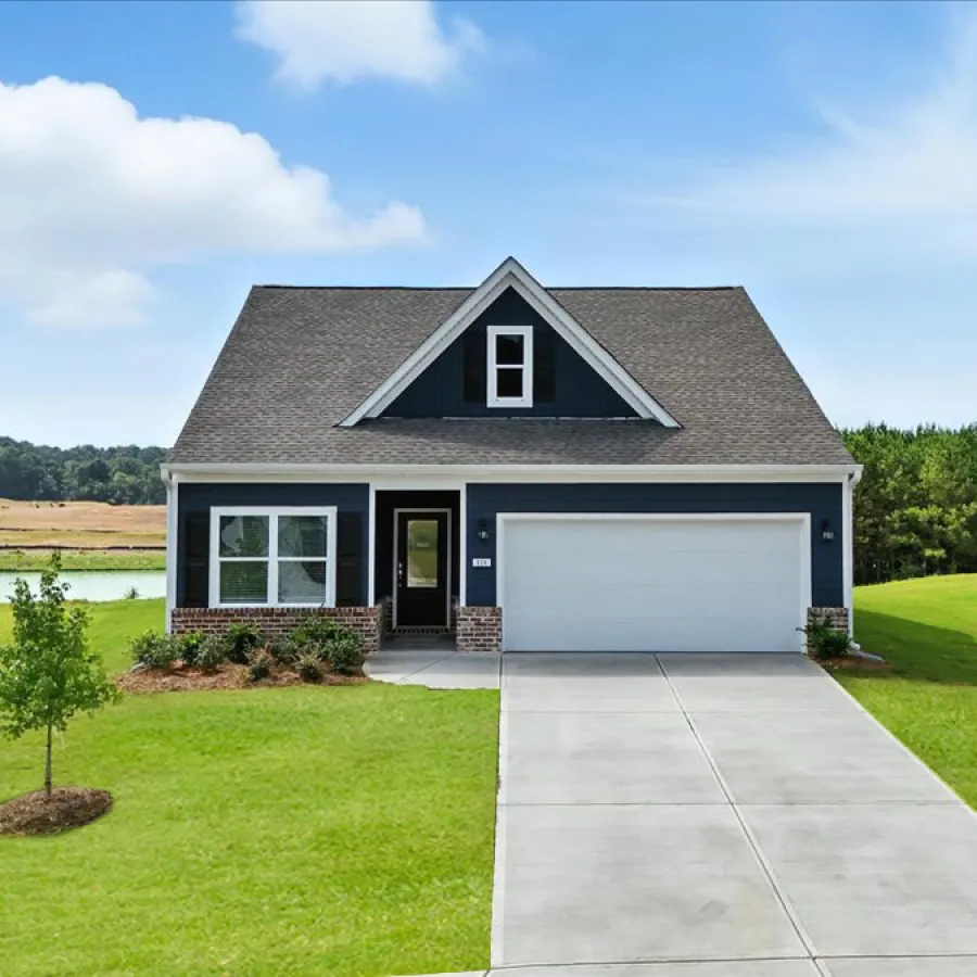 Single-story blue house with white trim, double garage, concrete driveway, and green lawn under a blue sky.