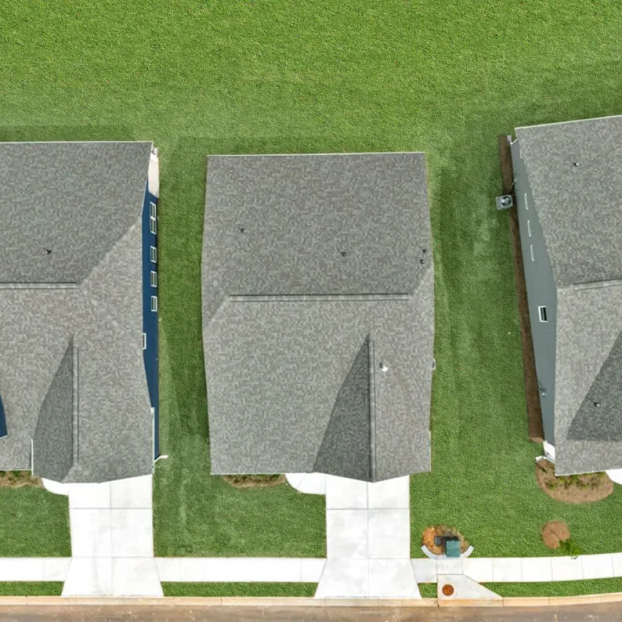 Aerial view of four suburban houses with grey roofs, green lawns, and concrete driveways in a row.
