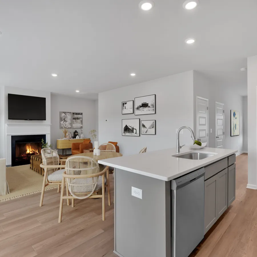 Open living room and kitchen with modern island, wooden flooring, fireplace, and neutral-toned furniture