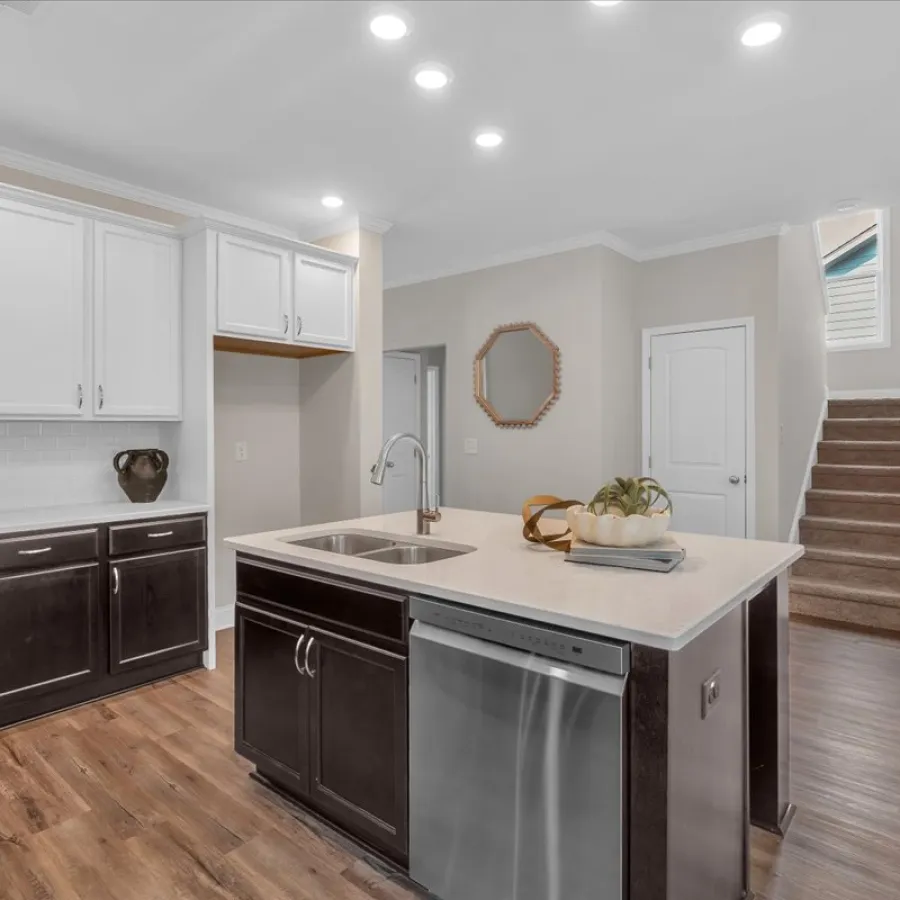 Modern kitchen with two-tone cabinetry, kitchen island with sink, stainless steel dishwasher, and wooden flooring.