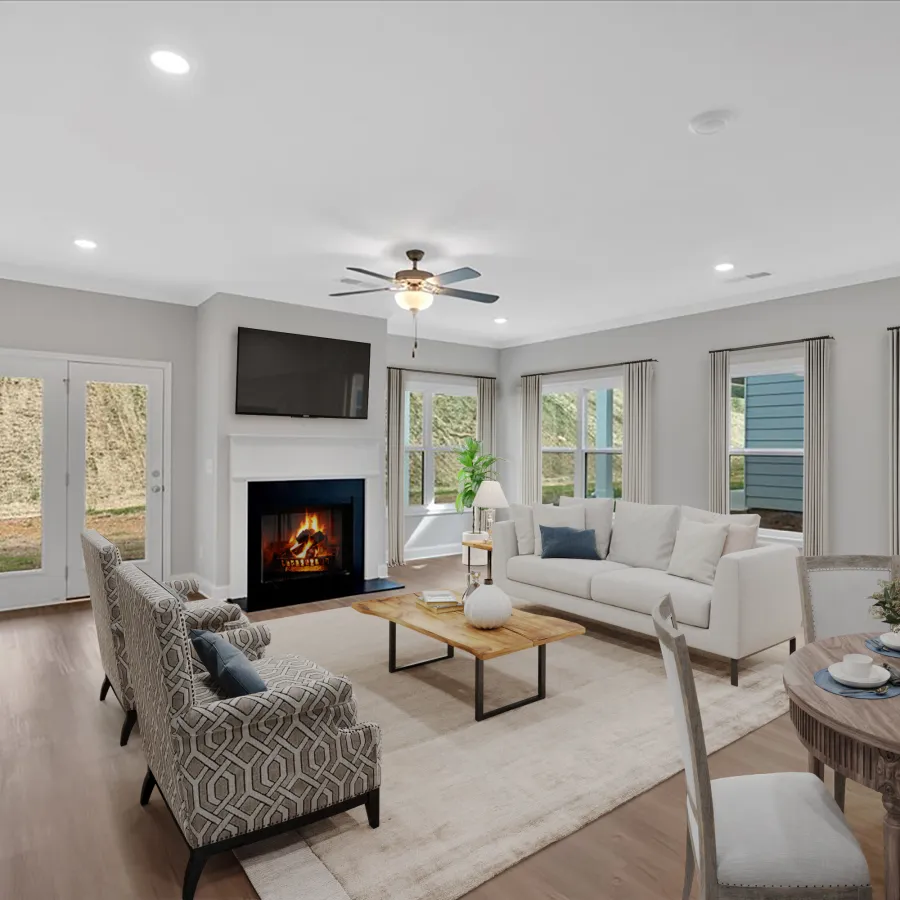 Bright modern living room with fireplace, white sofa, patterned chairs, wooden coffee table, and round dining table.
