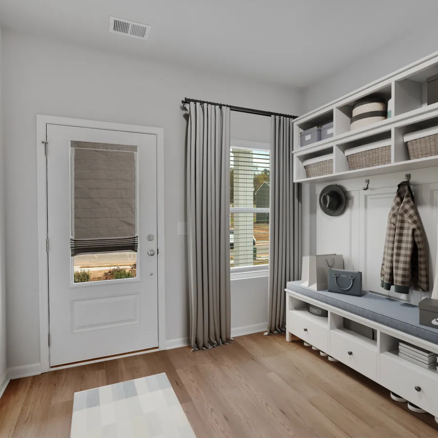 Modern mudroom with white storage bench, hooks, baskets, coats, window with curtains, and abstract wall art.