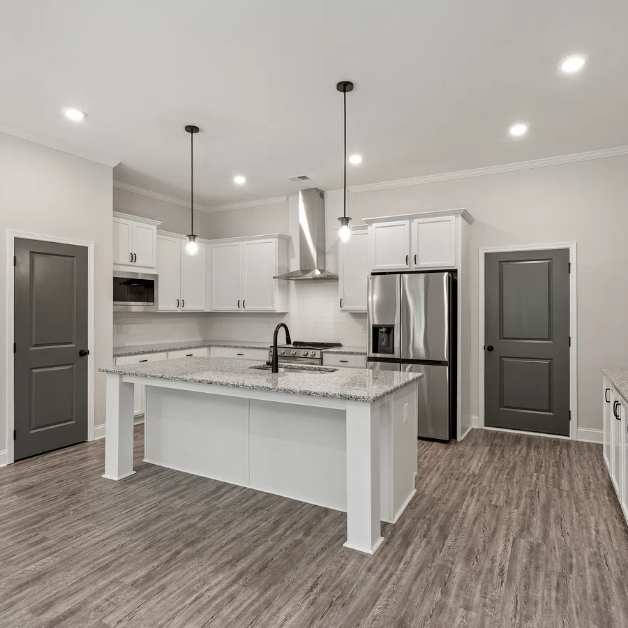Modern kitchen with white cabinetry, granite countertops, stainless steel appliances, and wood-look flooring under bright lighting