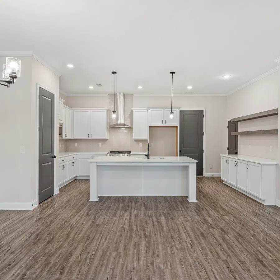Modern kitchen with white cabinetry, center island, wooden flooring, and black door accents under bright lighting.