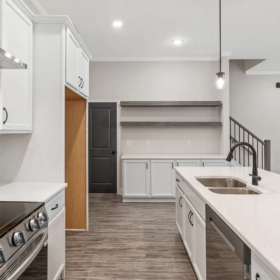 Modern kitchen with white cabinets, stainless steel appliances, quartz countertop island, and wood flooring
