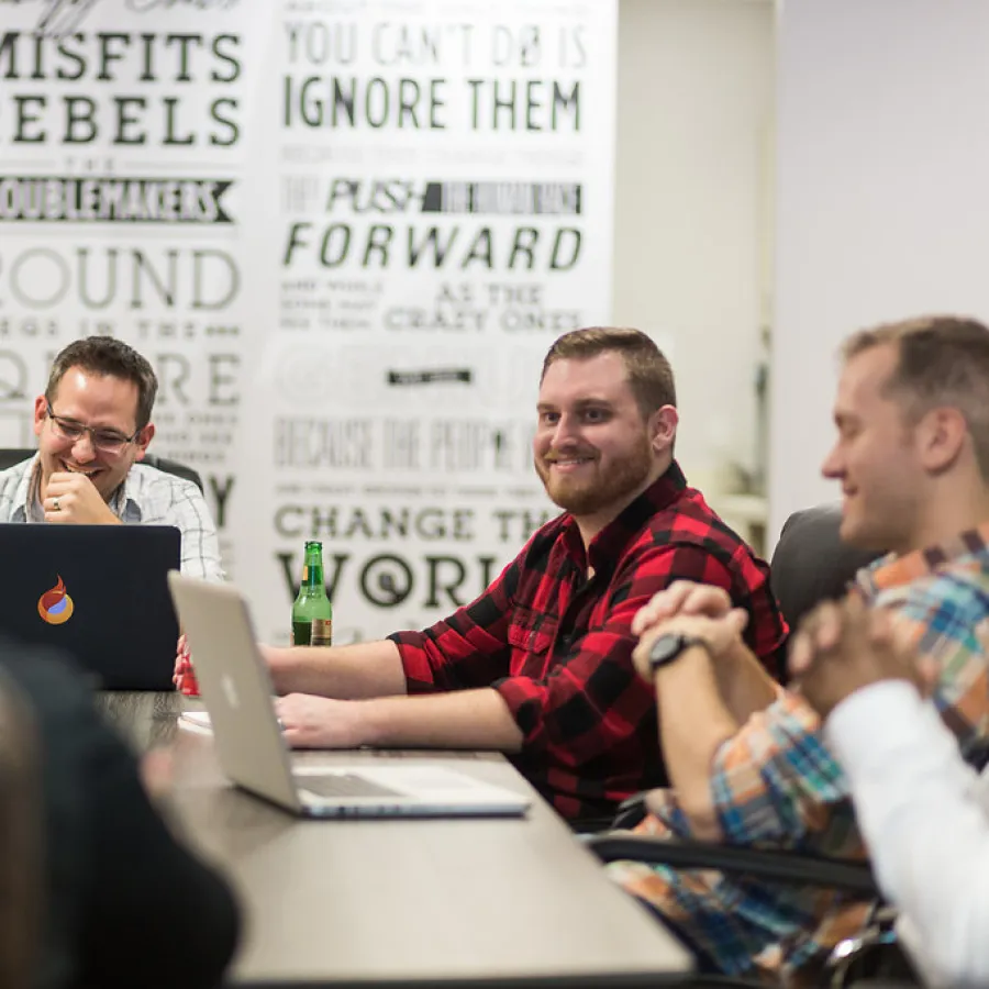 a group of men sitting at a table with laptops