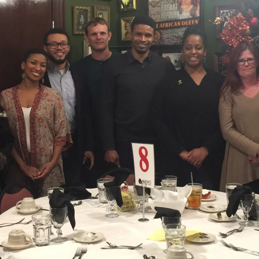 a group of people standing around a table with food and drinks