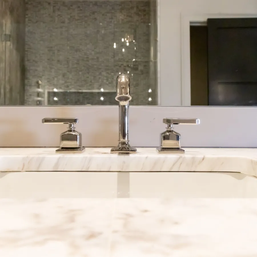 Close-up of a modern bathroom sink faucet and marble countertop in a sleek bathroom setting.