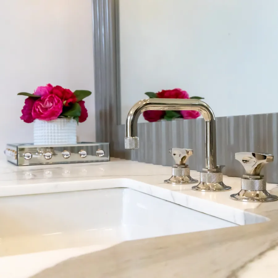 Elegant bathroom sink with modern faucet and pink floral arrangement in a stylish interior setting.