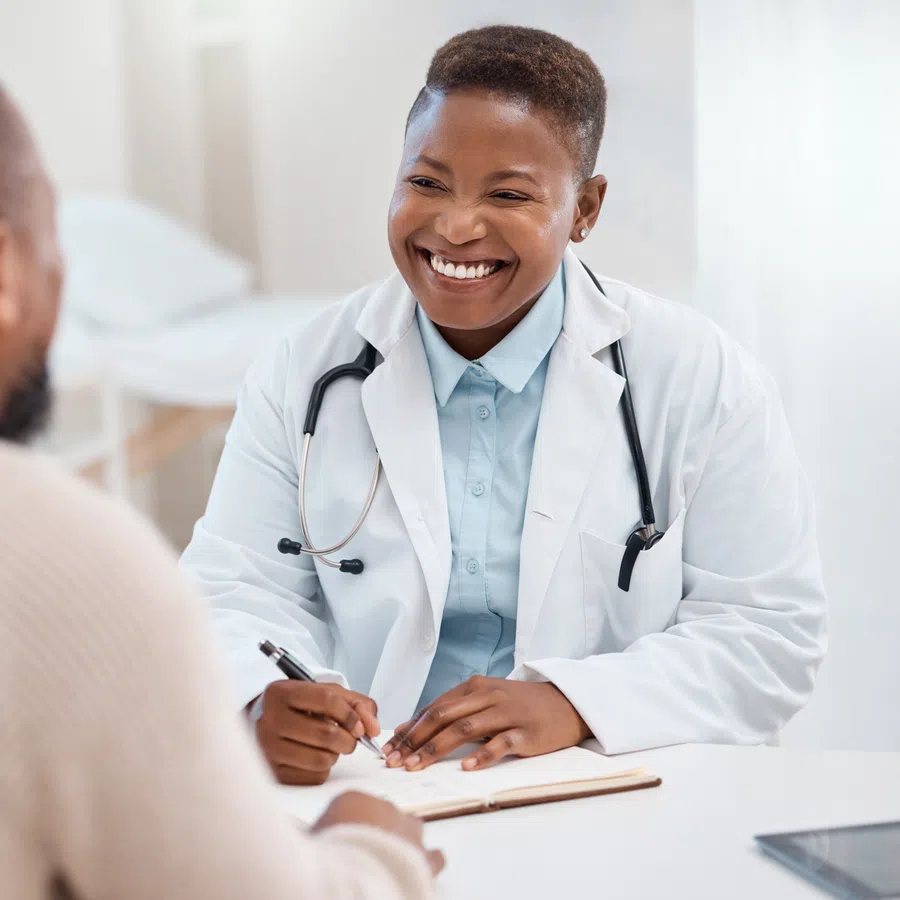 Smiling female doctor talking with male patient during consultation in a bright medical office.