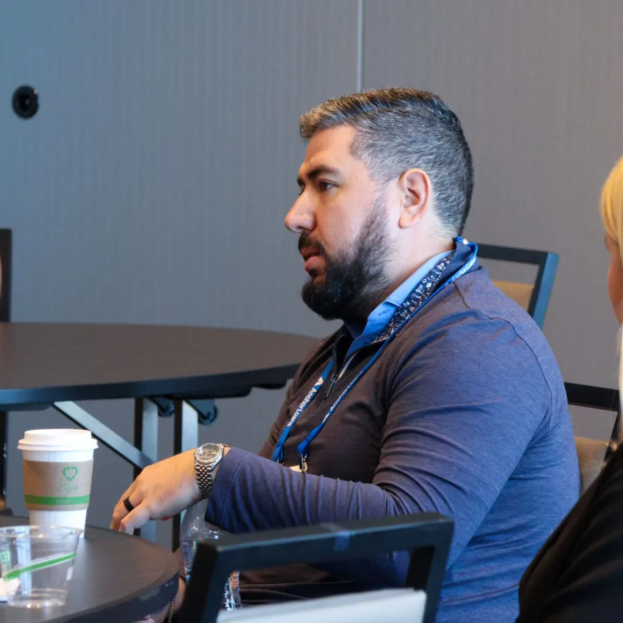 Man and woman seated at a round conference table during a discussion or meeting indoors.