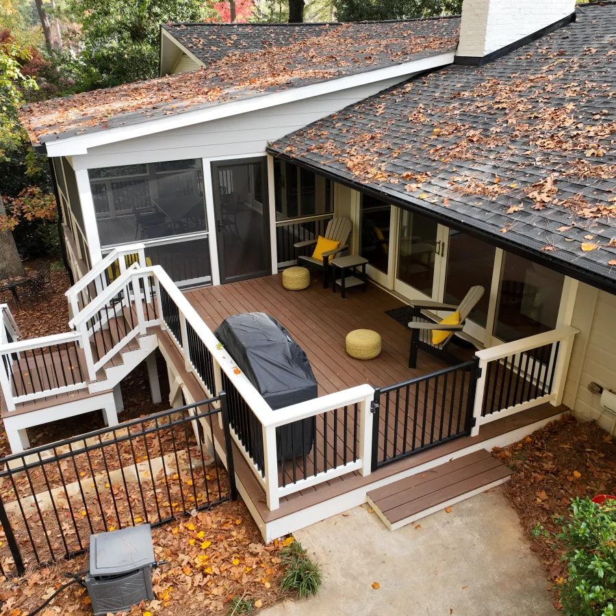 A cozy backyard deck with patio furniture and autumn leaves scattered on the ground.
