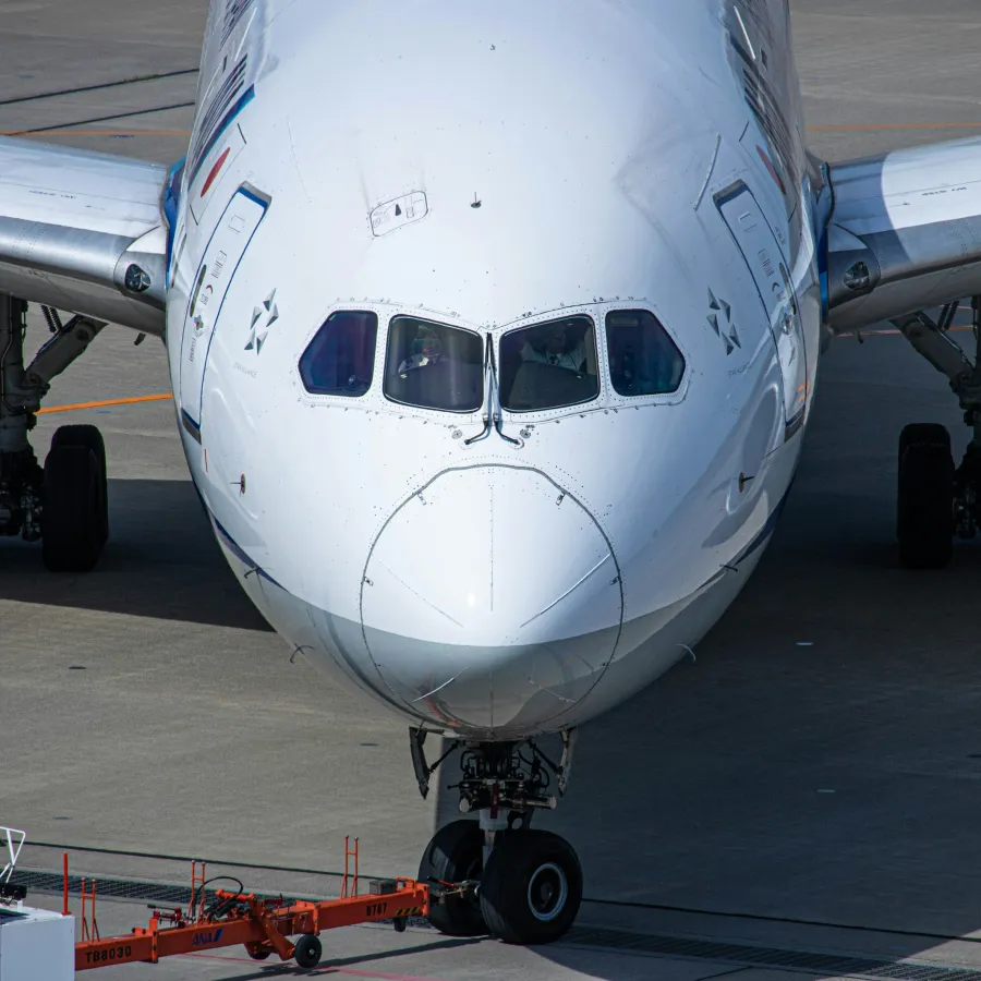 Close-up front view of a large commercial airplane on the runway with attached tow vehicle.