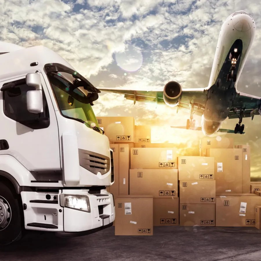 White delivery truck and airplane over stacked cardboard boxes at sunset in logistics hub.