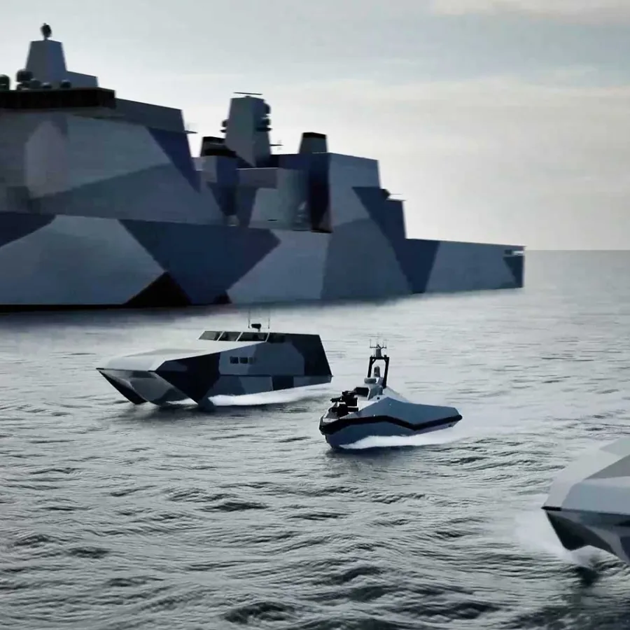 Four camouflaged naval ships including a large destroyer and three smaller vessels on calm sea under a cloudy sky.