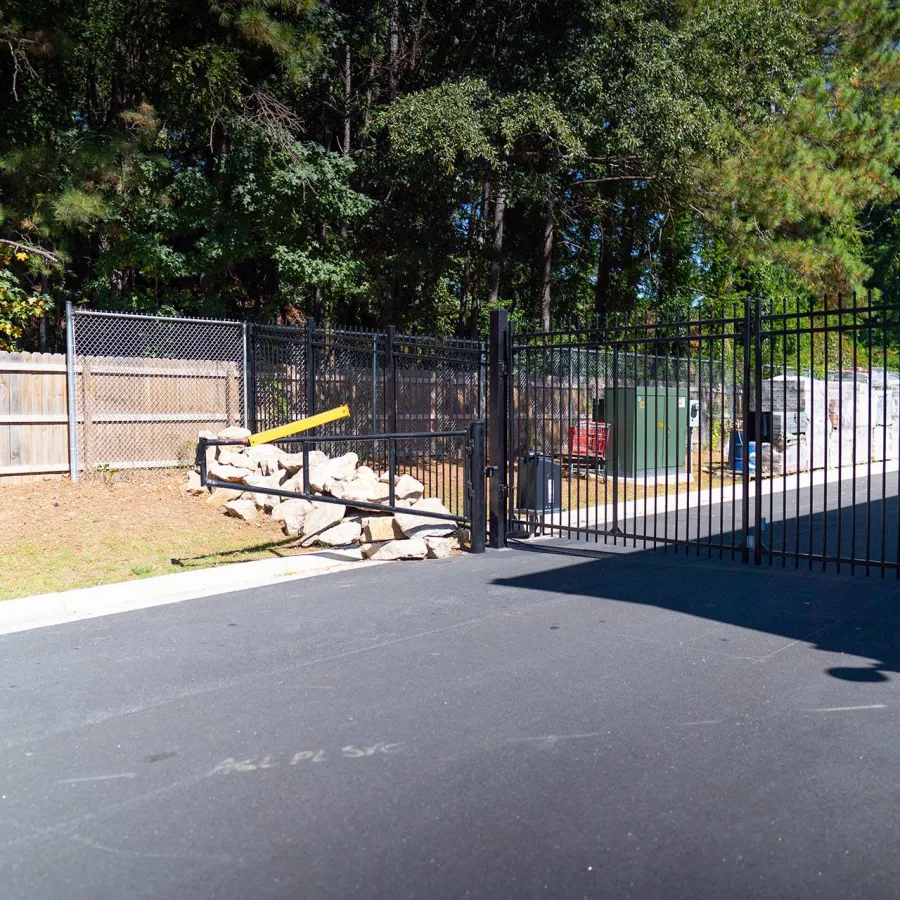 a fenced off area with a metal gate and trees in the background