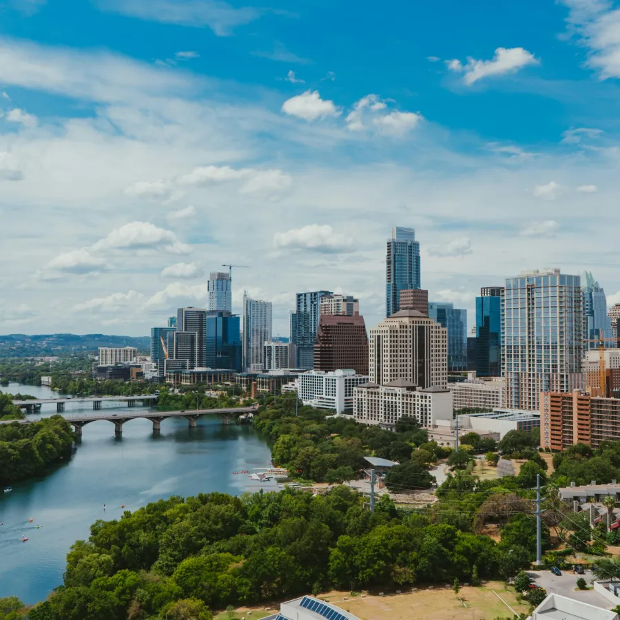 Vibrant city skyline of Austin, Texas with a river and blue sky in the background.