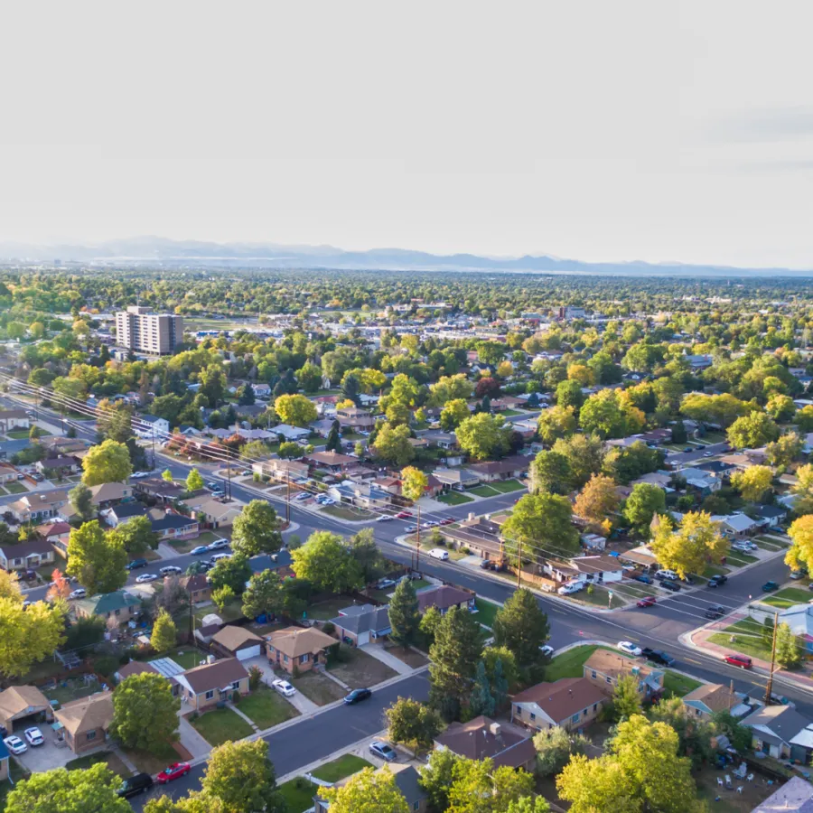 Aerial view of a vibrant suburban neighborhood with trees and homes under a clear sky.