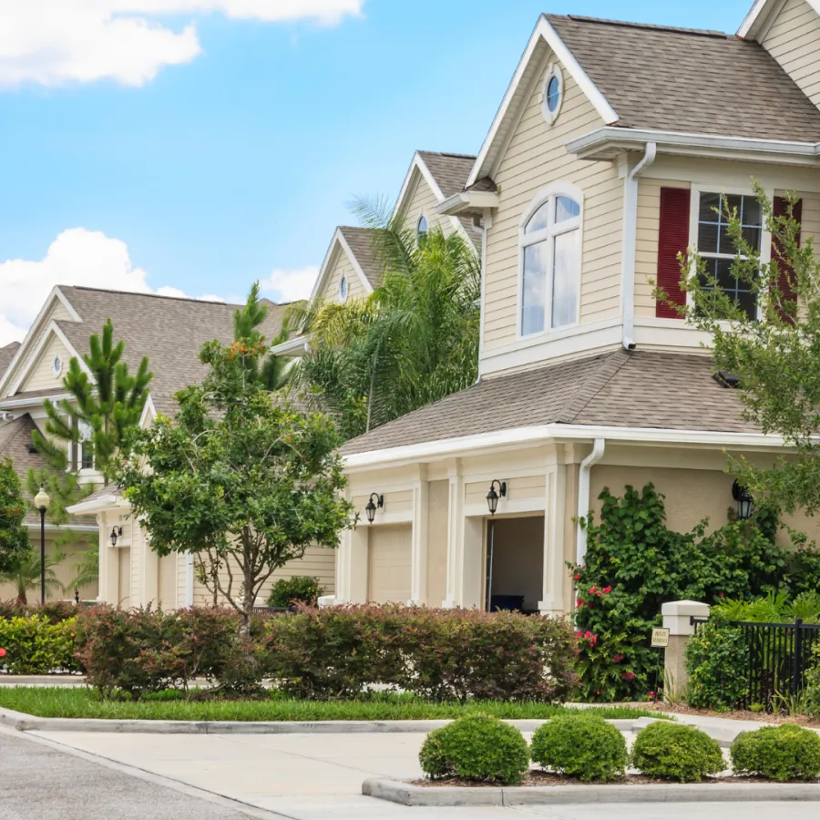 Row of elegant suburban homes with lush landscaping under a bright blue sky.
