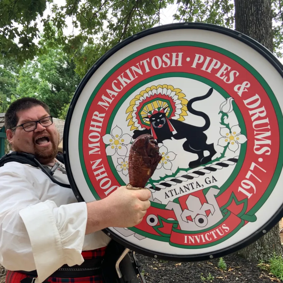 a person holding a bass drum and a turkey leg
