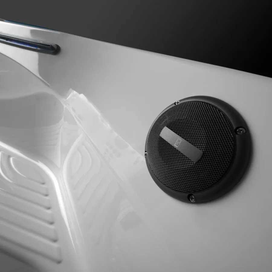 Close-up of a white hot tub interior with a black circular speaker and textured seating area.