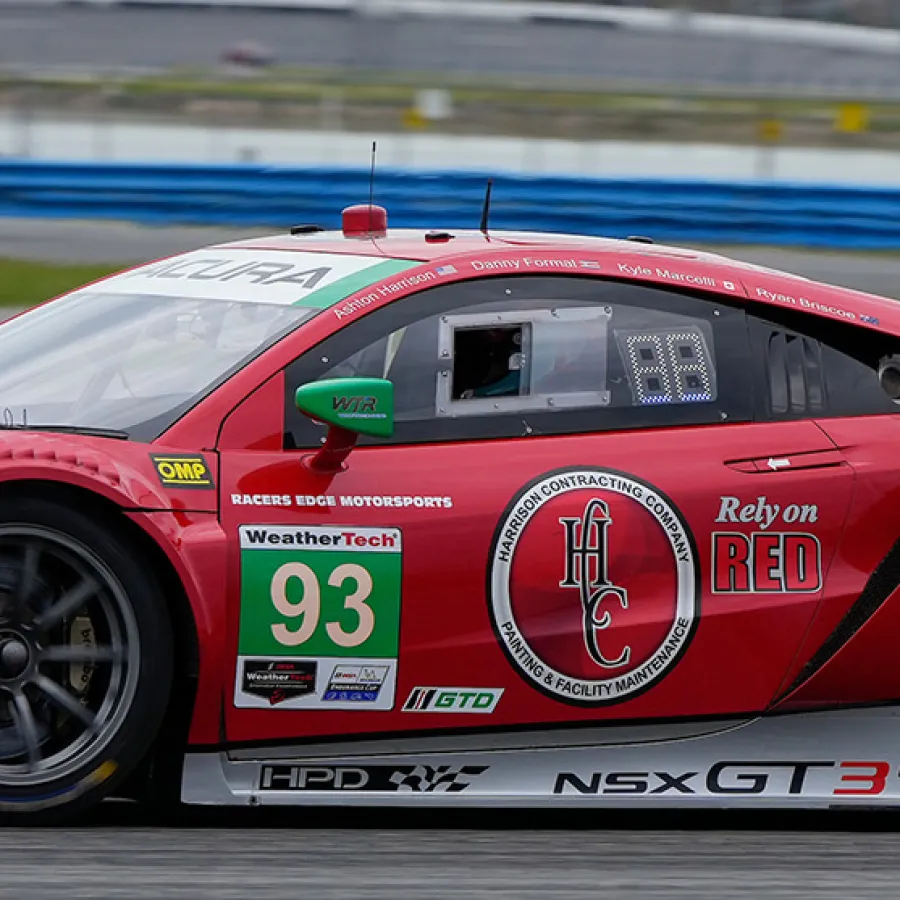 Red Acura NSX GT3 race car number 93 speeding on a racetrack with sponsor decals and aerodynamic design.