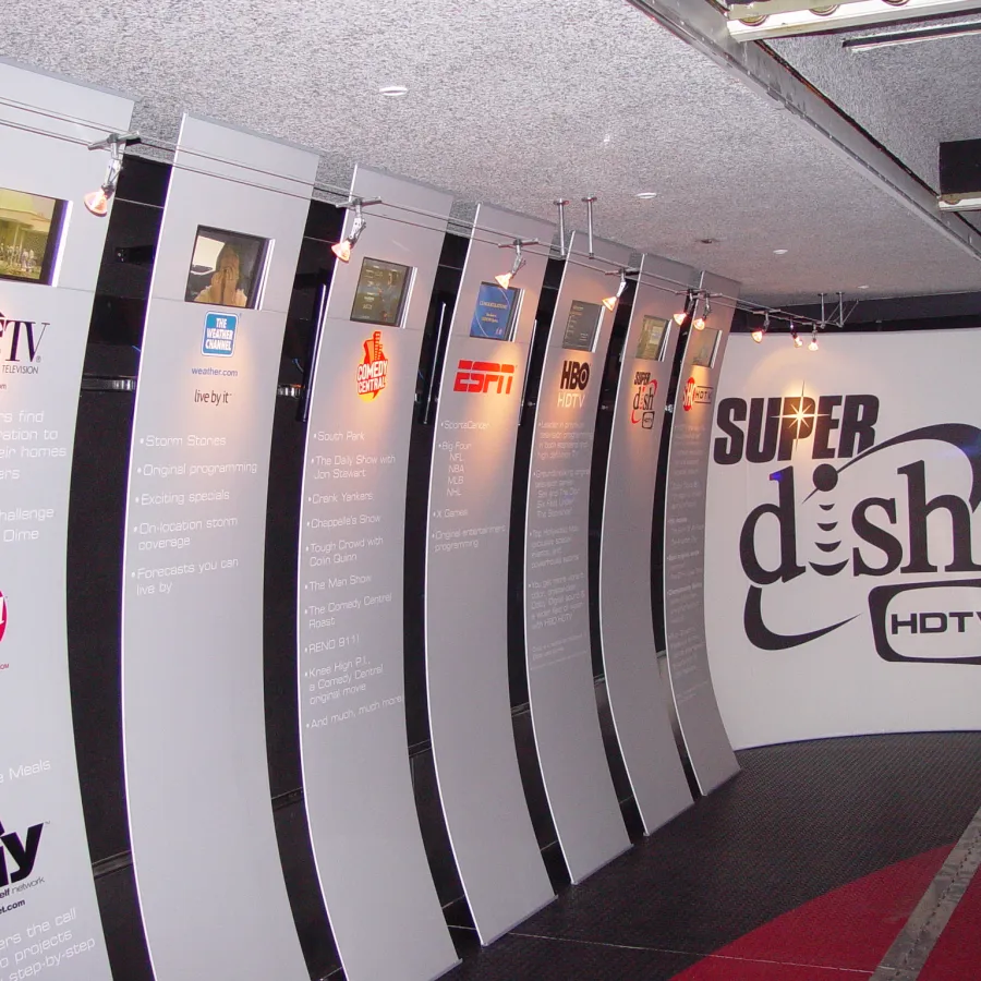 Curved panels displaying TV network logos and programming details with a large Super Dish HDTV logo on the wall.