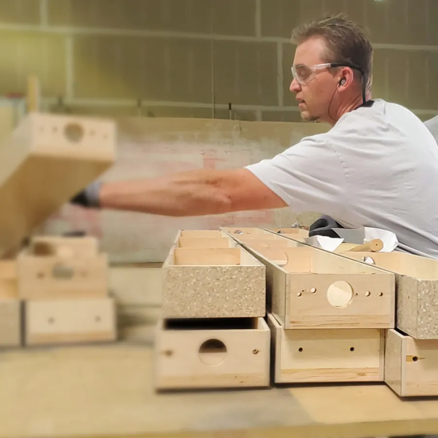 Carpenter assembling wooden drawer components on workbench in a woodworking shop