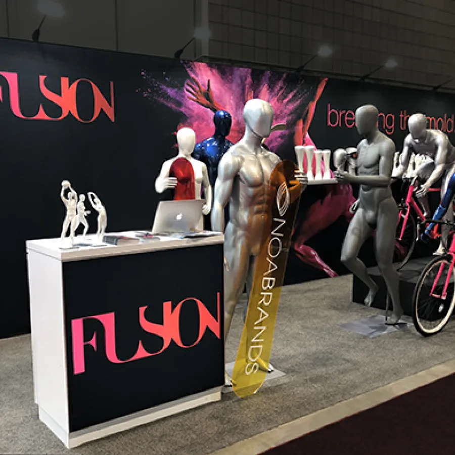 Trade show booth with Flyon logo, mannequins, bicycles, and promotional display for Noa Brands.