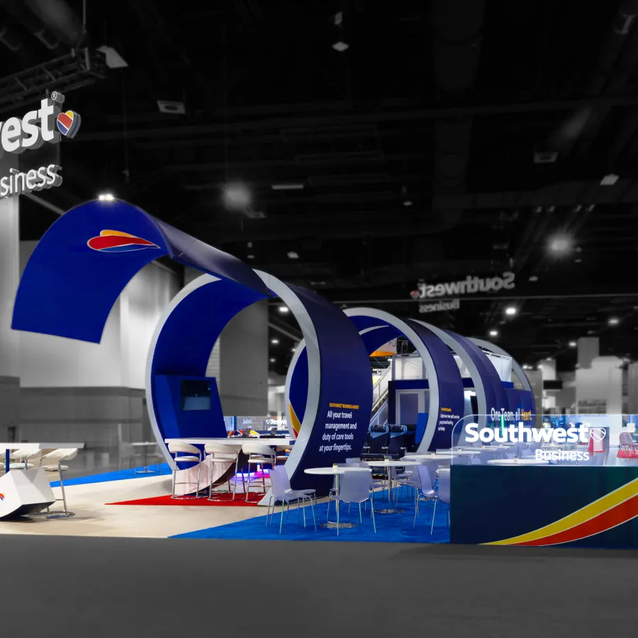 Southwest Business exhibition booth with blue curved structures and seating areas at a trade show.