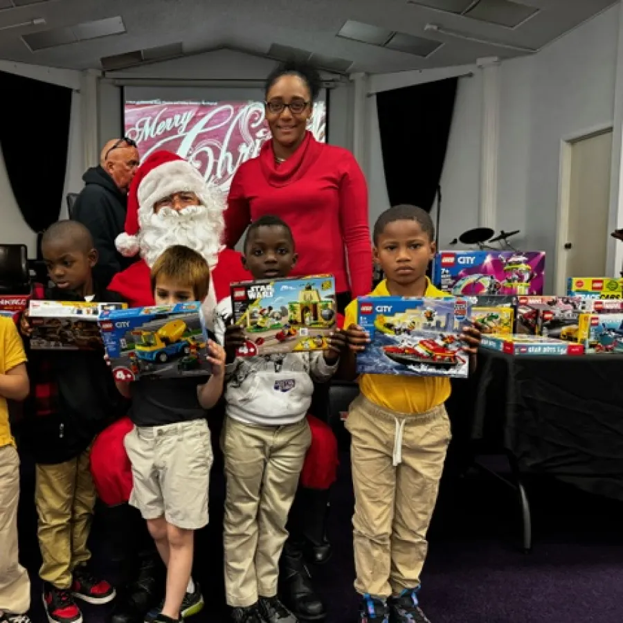 Children holding LEGO sets with Santa and a woman in a festive room celebrating Christmas together.