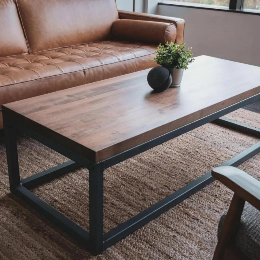 Modern living room with brown leather sofa, wooden coffee table, gray armchair, and a small plant on the table.