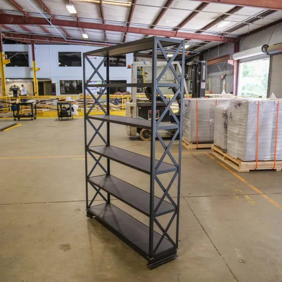 Black metal industrial shelving unit with four shelves standing in a spacious warehouse setting