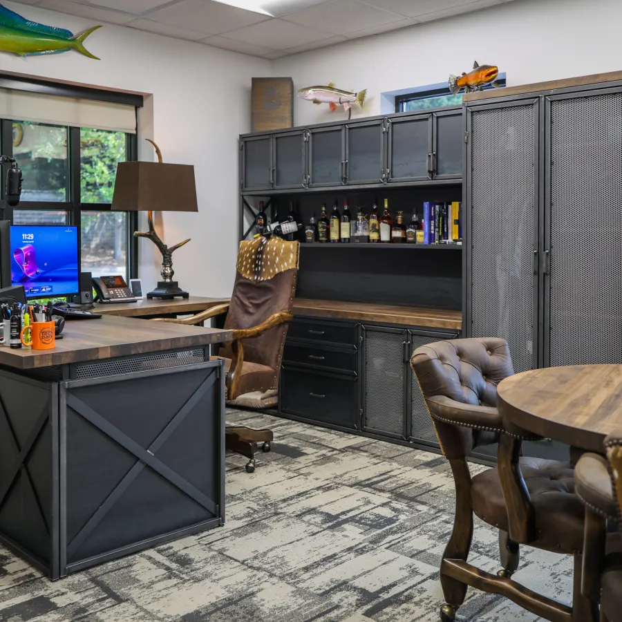 Modern home office with wood and metal furniture, leather chairs, computer desk, and decorative fish mounted on walls.
